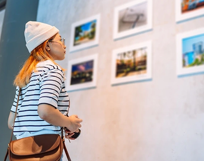 Une jeune femme observe des photos dans un musée