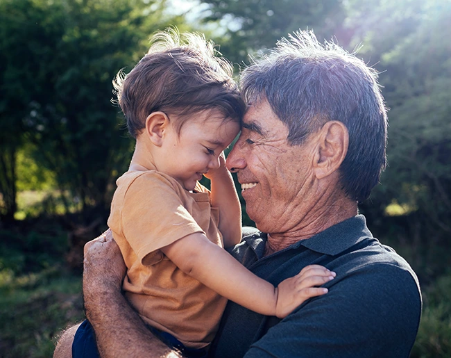 Un grand père porte son petit fils dans les bras